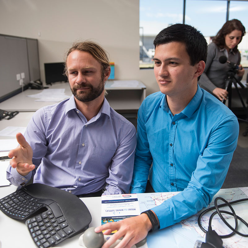 Two men at a computer with woman behind them