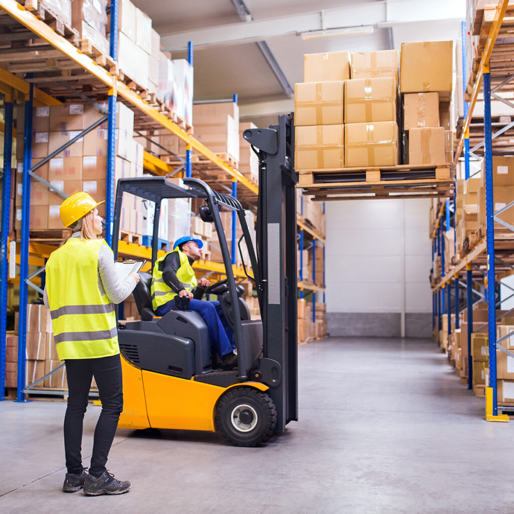 Machinery safety concept - Workers in a warehouse moving goods with a forklift